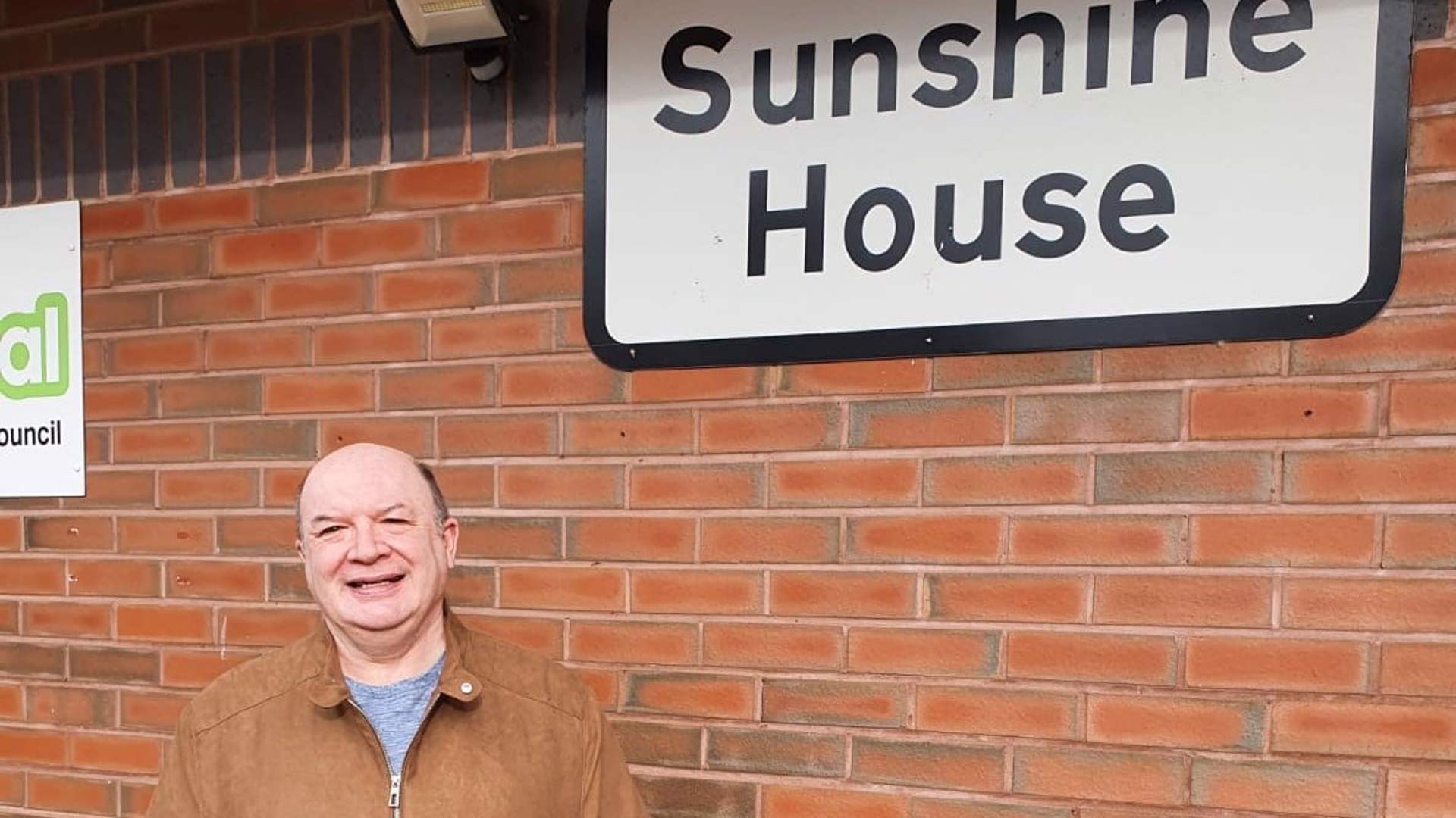 man standing next to a sign that says Sunshine House
