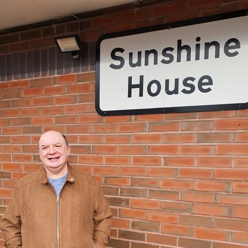 man standing next to a sign that says Sunshine House