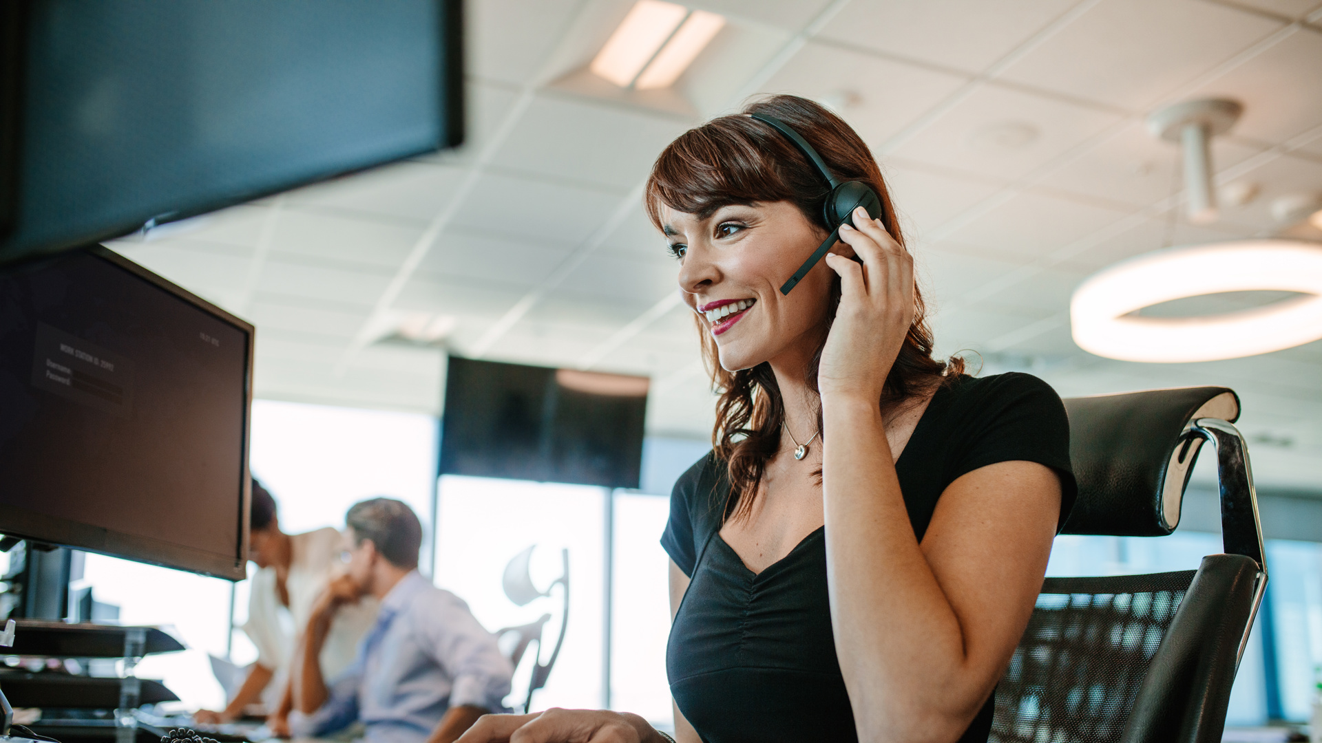 Woman in an office on a computer with a headset 